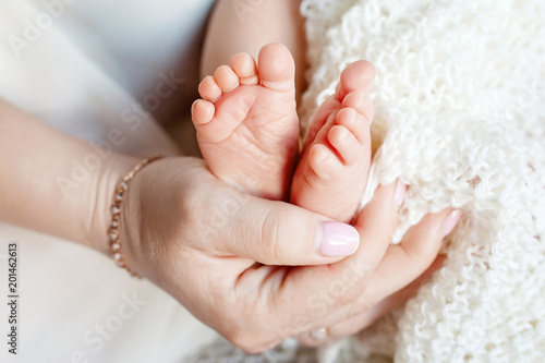 Baby feet in mother hands. Tiny newborn baby's feet on female shaped hands closeup. Mom and her child. Beautiful conceptual image of Maternity