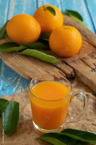 Fresh orange and a glass of orange juice on a wooden table background