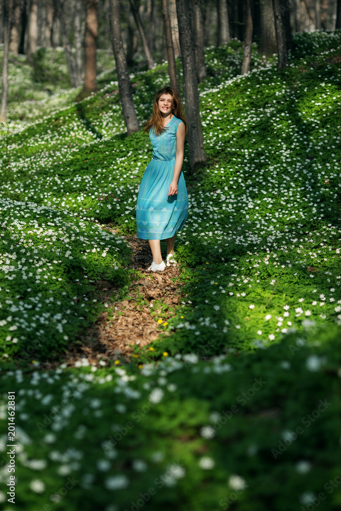 Woman runs through the forest in a long dress. Relaxing woman at nature. Happy pretty young woman enjoying smell flowers over spring forest background Woman runs through the forest in a long dress. Relaxing woman at nature. Happy pretty young woman enjoying smell flowers over spring forest background