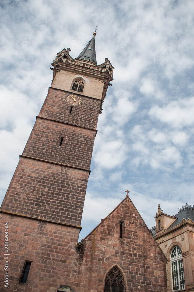 Medieval architecture in Obernai in Alsace France. The chapel tower on beautiful cloudy sky background Medieval architecture in Obernai in Alsace France. The chapel tower on beautiful cloudy sky background