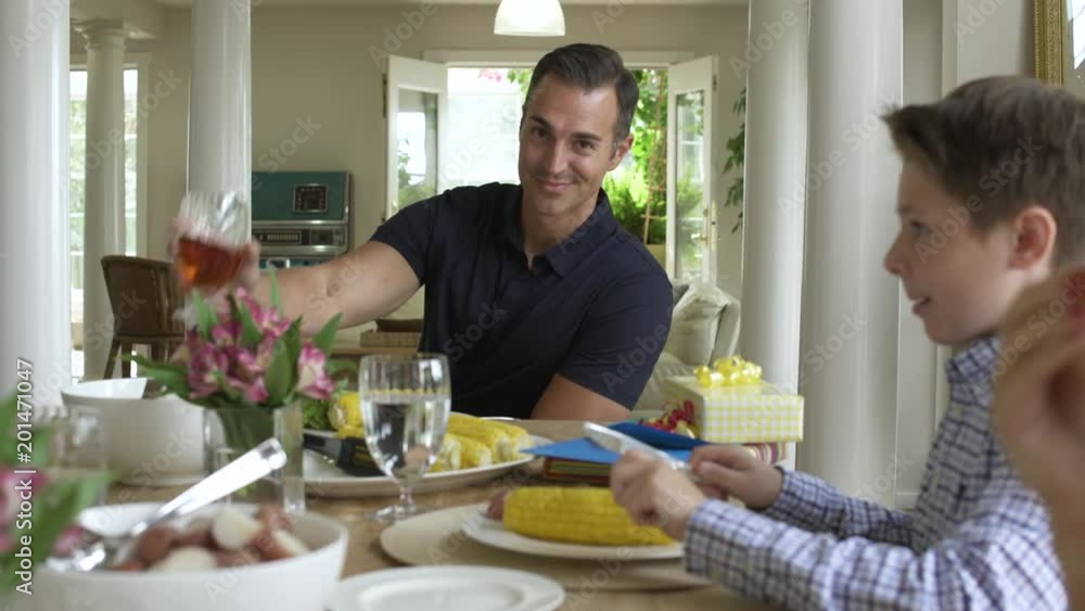 Father dining with family, looking at camera making a toast. Father dining with family, looking at camera making a toast.