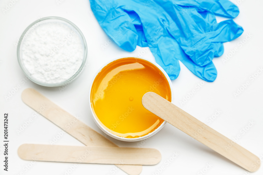 Wax for depilation with blue gloves and other tools on a white background, top view Wax for depilation with blue gloves and other tools on a white background, top view