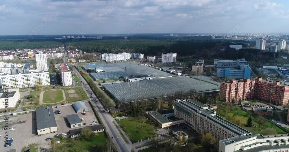 Panorama from height, view of greenhouses, reflections in glass, city landscape aerial view.
