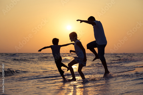 Father son and daughter playing on the beach at the sunset time.