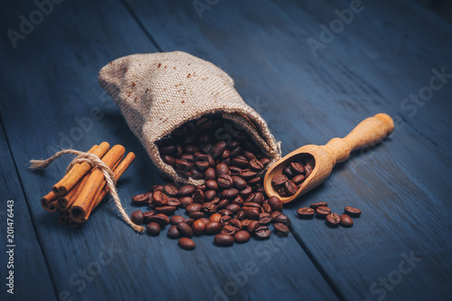 Fried coffee beans in a sackbag and wooden spoon on a blue textured background with copy space. Minimalist design for advertising in a cafe, top view. photo