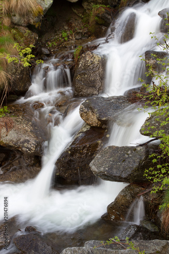 Fototapeta Naklejka Na Ścianę i Meble -  Small waterfall of a creek downhill to the Gran Paradiso National Park
