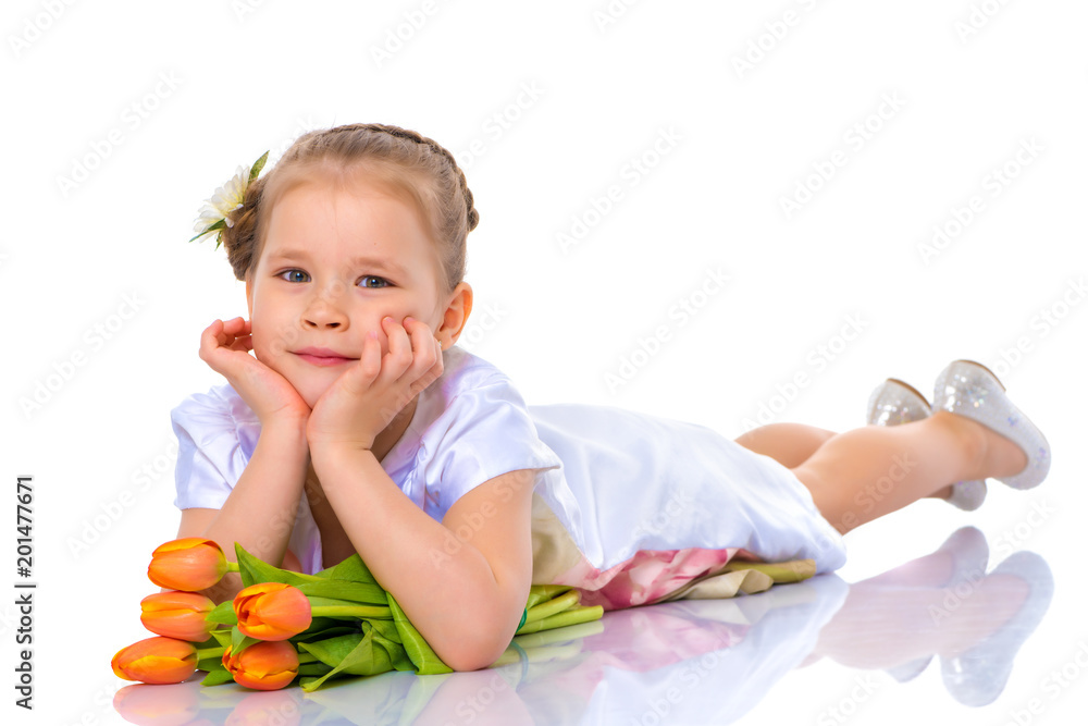 A little girl is lying on the floor with a bouquet of tulips. A little girl is lying on the floor with a bouquet of tulips.