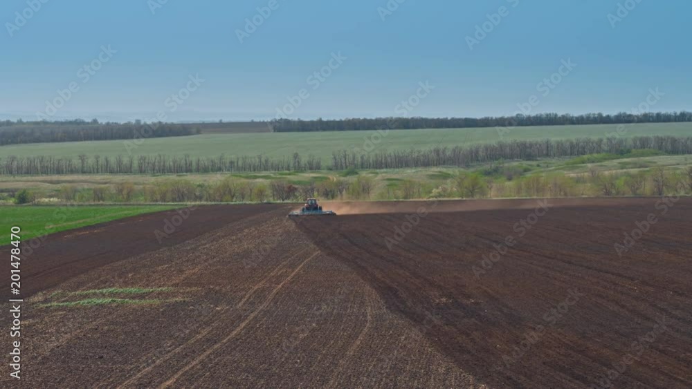 Farmer In Tractor Preparing Land In Early Spring Season Farmer In Tractor Preparing Land In Early Spring Season