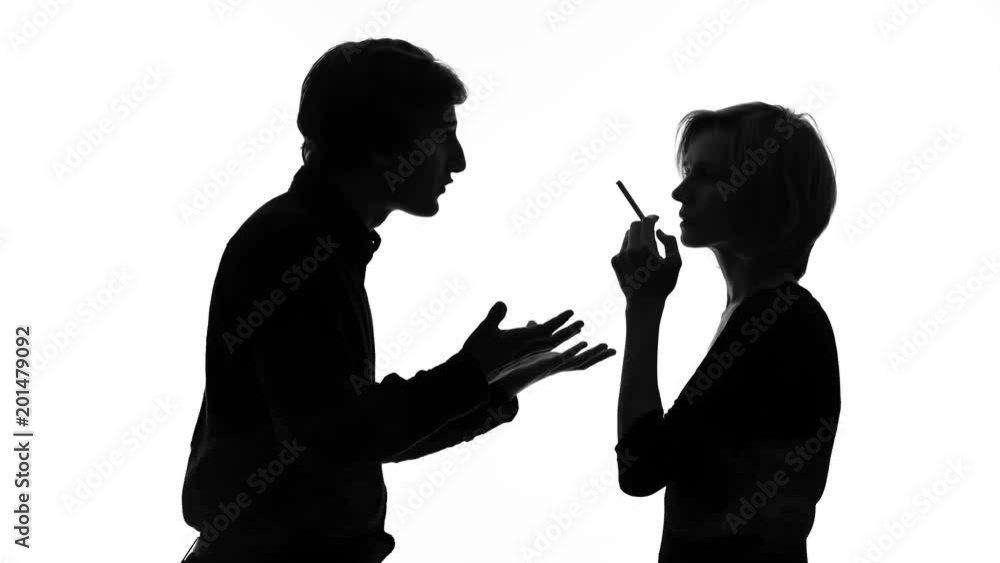 Angry man shouting at his girlfriend smoking cigarette in front of him, quarrel Angry man shouting at his girlfriend smoking cigarette in front of him, quarrel