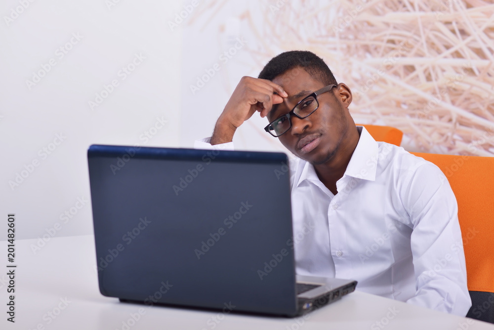 Handsome Afro American businessman in classic suit is using a laptop and smiling while working in office Handsome Afro American businessman in classic suit is using a laptop and smiling while working in office