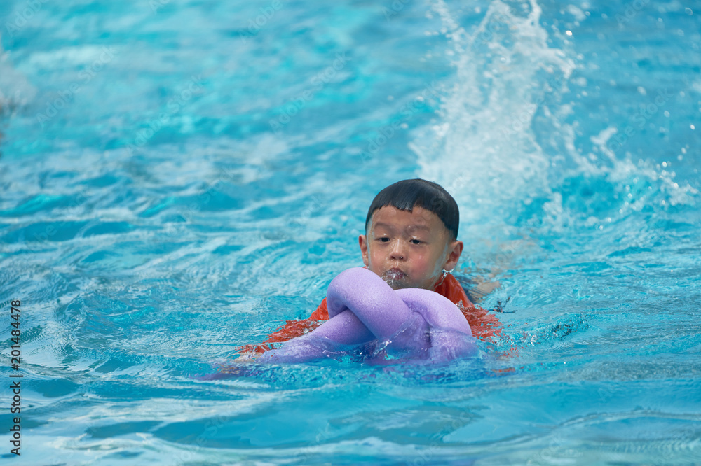 Boy practice swimming with noodle foam floater