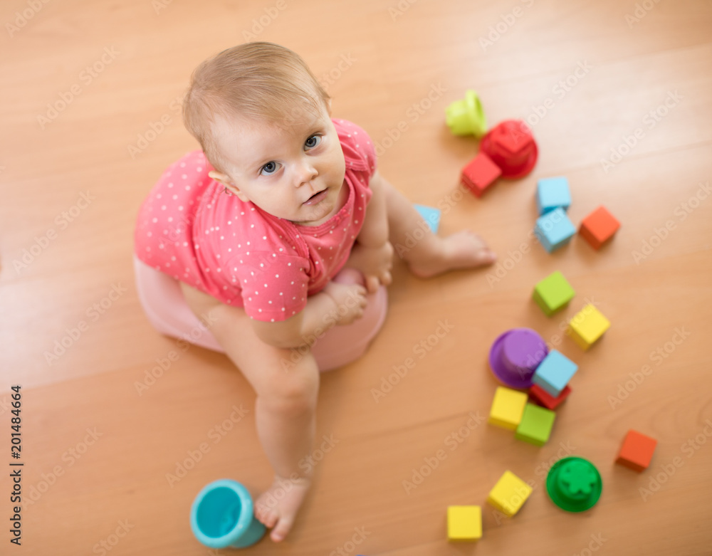 Baby sits on chamber pot, toilet, playing with toys. Top view. Baby sits on chamber pot, toilet, playing with toys. Top view.