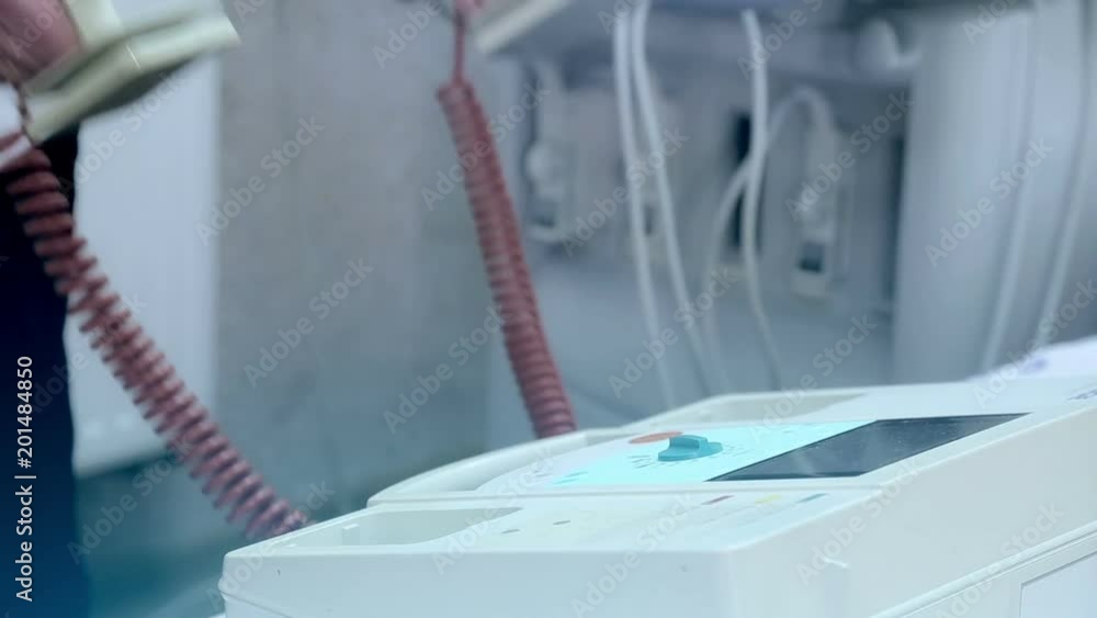 The doctor takes the defibrillator in his hands and puts the defibrillator in place