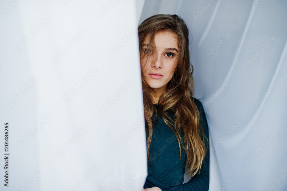 Handsome brunette girl wear on green, posing at curtains. Studio model portrait. Handsome brunette girl wear on green, posing at curtains. Studio model portrait.