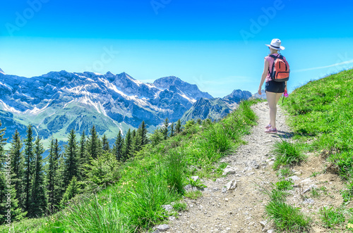 The girl travels along the mountain path upwards against the background of the Alpine landscape
