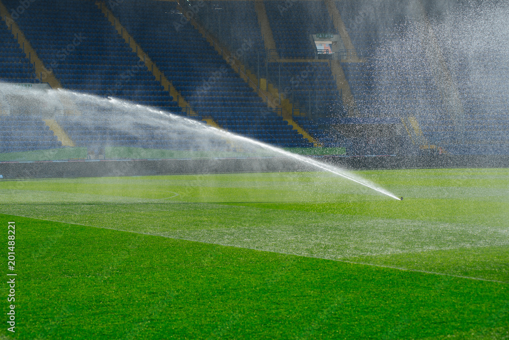Irrigation turf. Sprinkler watering football field. System working on fresh green grass on football or soccer stadium.