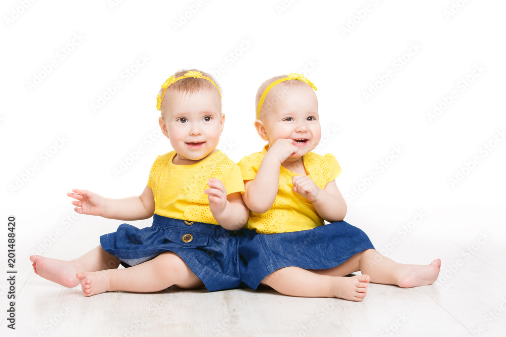 Babies Twins, Two Kids Girls Sitting on Floor, Happy Children Portrait, Sisters Isolated over White Background Babies Twins, Two Kids Girls Sitting on Floor, Happy Children Portrait, Sisters Isolated over White Background