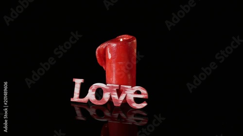 A single burning red candle rotate isolated in front of black background photo