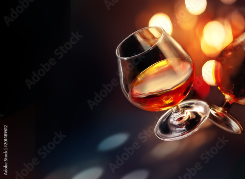 Cognac wineglass with colorful festive lighting on black background