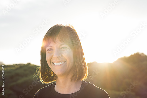 Normal brunette girl smiling. Woman with a smile on a sunset