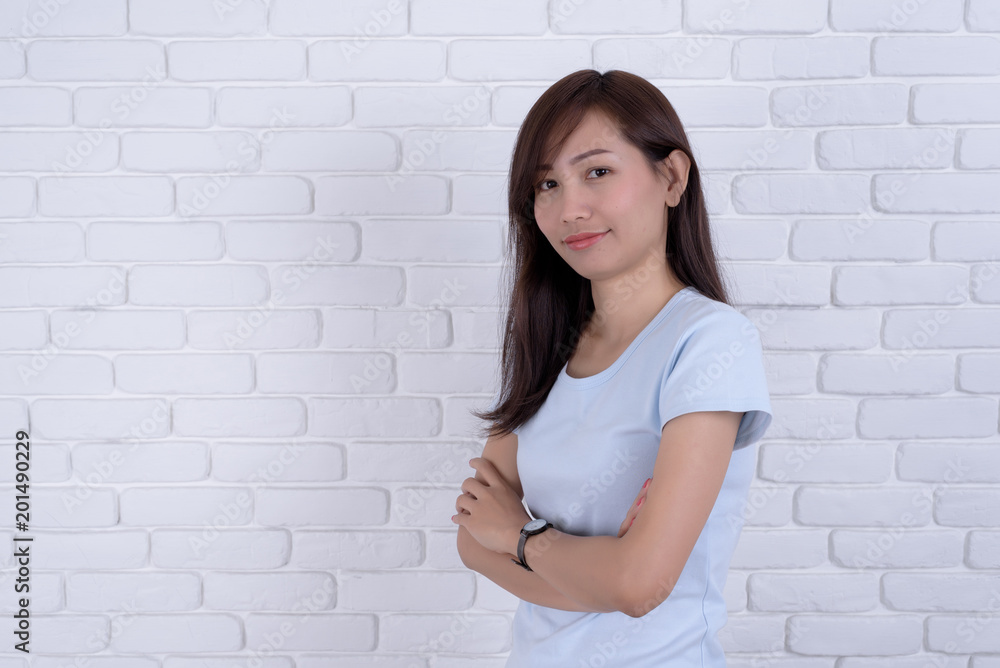 Smiling beautiful woman standing and points against a white brick wall. Girl at White Brick Wall Background.