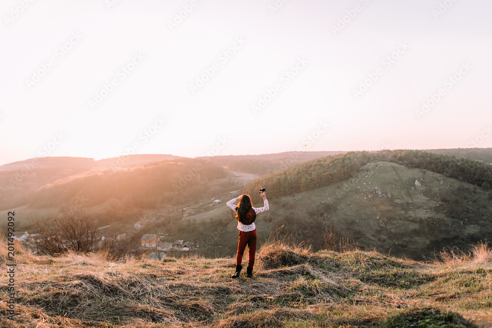 Portrait of girl with a binoculars on top of the mountains walking at sunset
