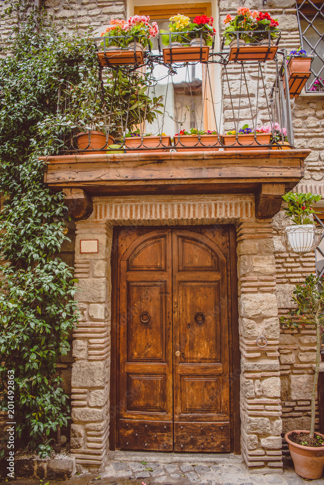 old building with wooden doors and potted plants on balcony in Castel Gandolfo, Rome suburb, Italy