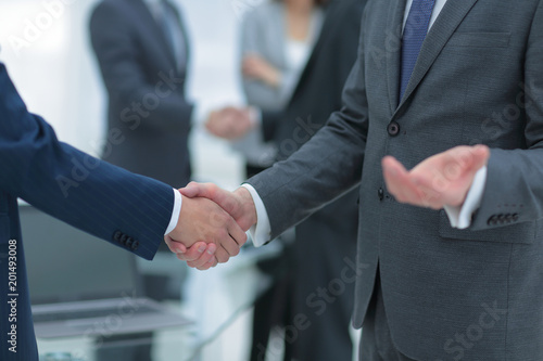 Business partners handshaking over business objects on workplace © ASDF