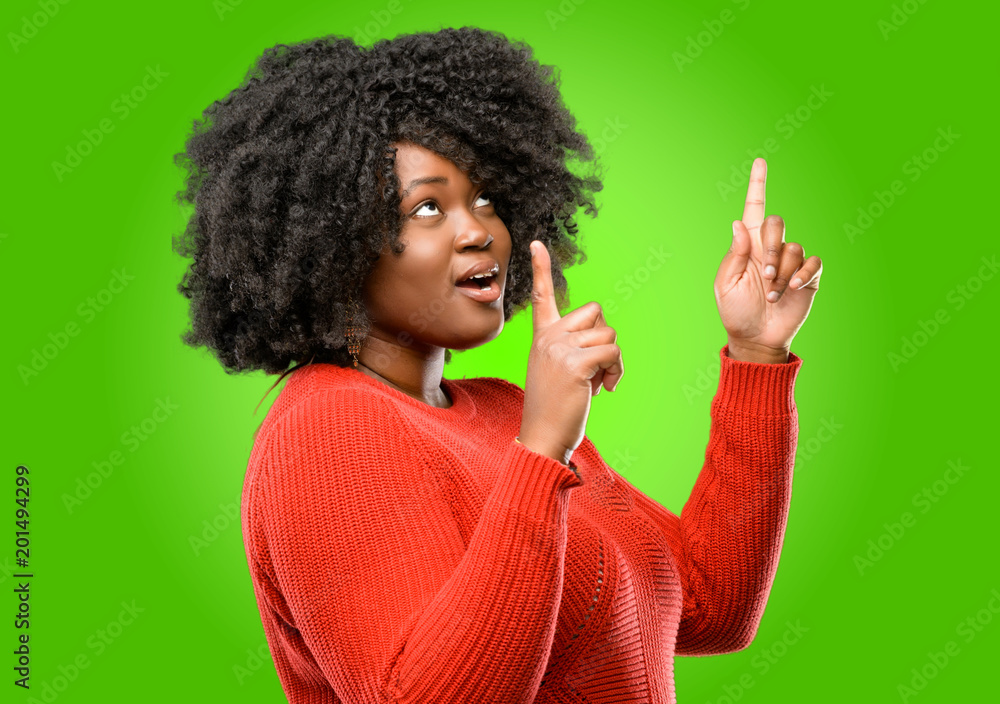 Beautiful african woman happy and surprised cheering expressing wow gesture pointing up Beautiful african woman happy and surprised cheering expressing wow gesture pointing up