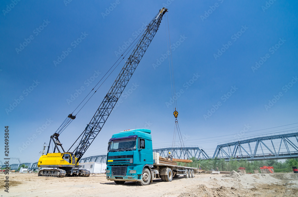 The crane loads the metal structures onto the truck The crane loads the metal structures onto the truck