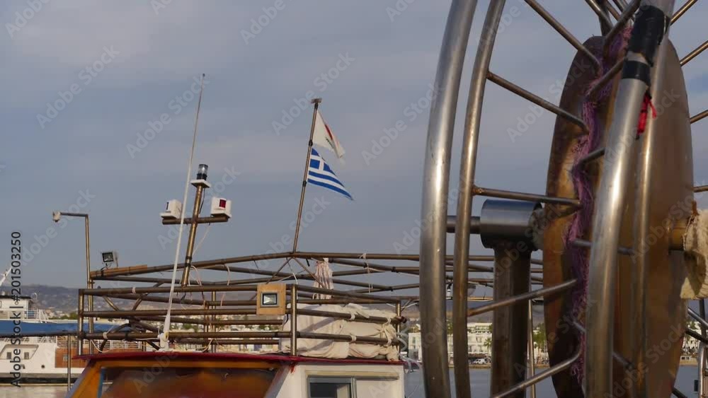 Greek flag on a docked fishing boat waves with the wind in the afternoon Greek flag on a docked fishing boat waves with the wind in the afternoon