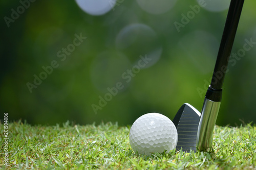 Piłka golfowa na zielonej trawie przygotowywającej uderzającą na pola golfowego tle