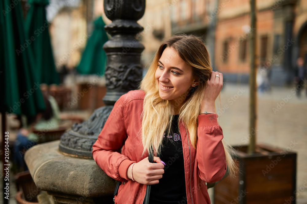 Fototapeta premium Beautiful girl posing on the city street and smile to camera