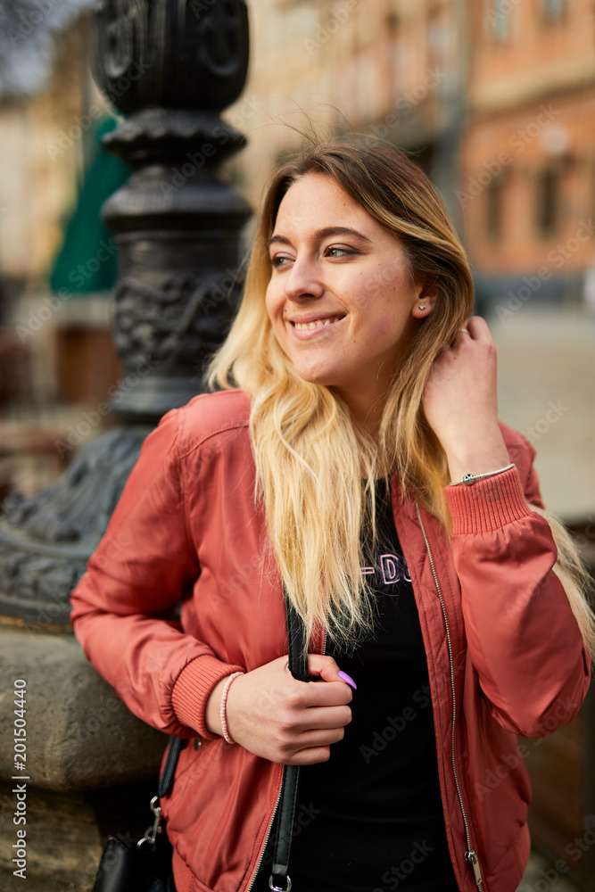 Beautiful girl posing on the city street and smile to camera