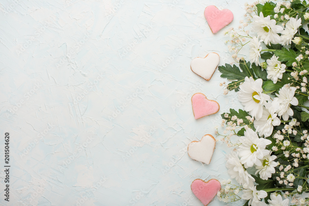 White chrysanthemums on a wooden background and homemade cookies in the form of hearts, with an empty space for writing or advertising White chrysanthemums on a wooden background and homemade cookies in the form of hearts, with an empty space for writing or advertising