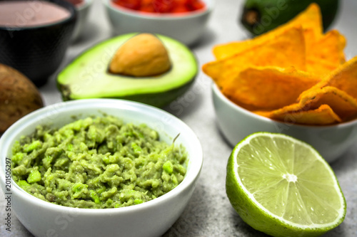 Traditional mexican sauce - guacamole dip with avocado and tortilla chips snack on table, party food for sharing