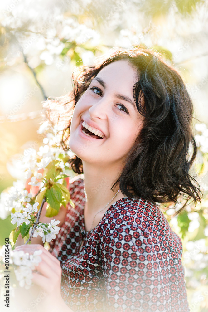 beauty, spring, floral arrangement concept. surrounded by flowers of blooming cherry trees there is a laughing woman with small straight nose, dark eyes and hair beauty, spring, floral arrangement concept. surrounded by flowers of blooming cherry trees there is a laughing woman with small straight nose, dark eyes and hair