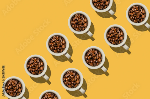 Cup concept. White cups with coffee beans on yellow background.  Creative style.