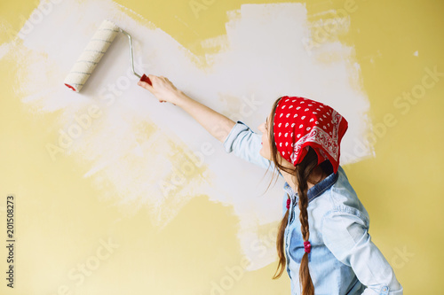 Portrait of a young beautiful woman painting wall in her new apartment photo