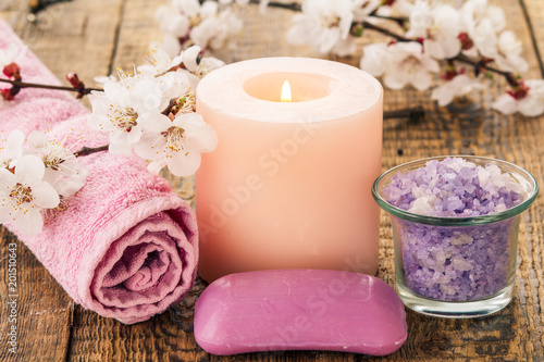 Soap  sea salt in glass bowl with towel for bathroom proceduresl and  burning candle with flowering branch of apricot tree