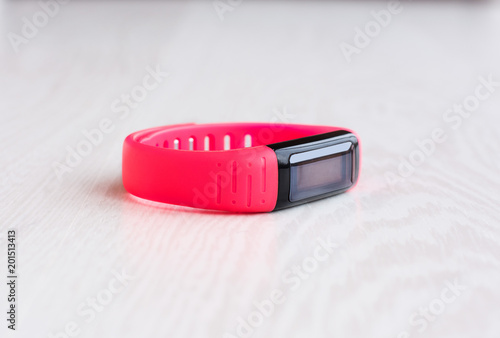 Pink fitness bracelet with place for text on a white wooden background