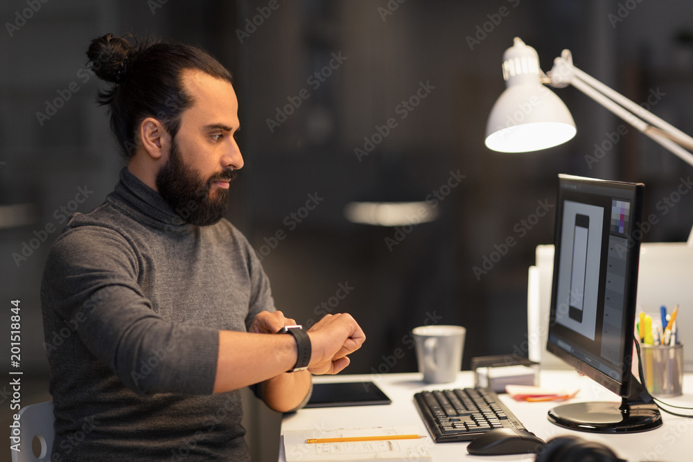 deadline, technology and people concept - creative man or graphic designer with smartwatch and computer working late at night office deadline, technology and people concept - creative man or graphic designer with smartwatch and computer working late at night office