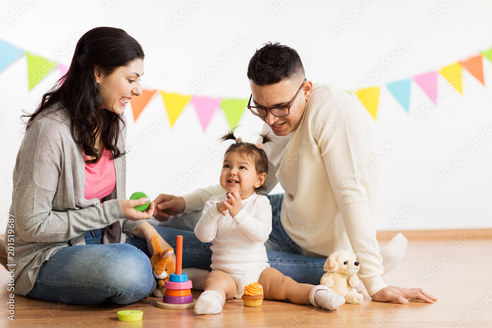 family, holidays and people concept - happy mother, father and little daughter playing with toys on birthday party family, holidays and people concept - happy mother, father and little daughter playing with toys on birthday party