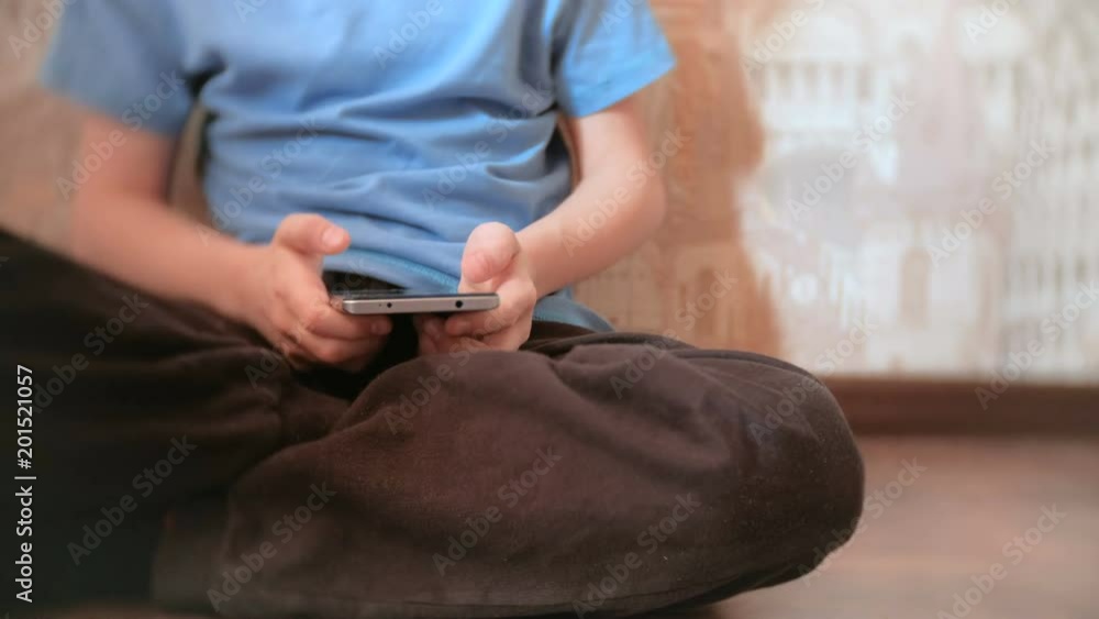Unrecognizable seven-year-old boy browsing internet on his mobile phone Unrecognizable seven-year-old boy browsing internet on his mobile phone