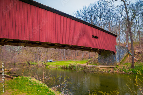 Outdoor view of red covered bridge inside of the forest over a small river in Lancaster © Fotos 593