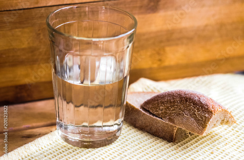 A glass of vodka and a piece of bread on a wooden table