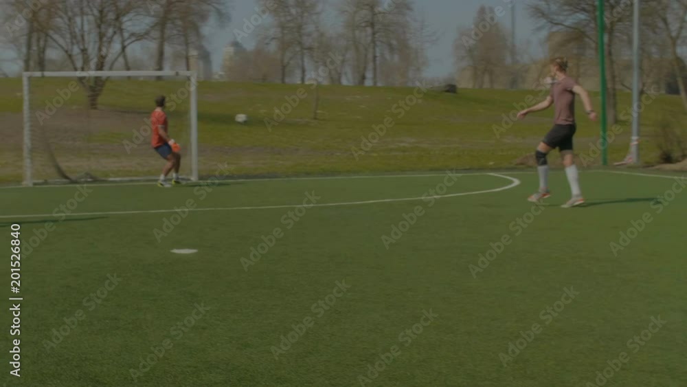 Young soccer player kicking a soccer ball attempting to score goal during football training session in the pitch. Teenageer footballer taking a shot on goal during football match on sports field. Young soccer player kicking a soccer ball attempting to score goal during football training session in the pitch. Teenageer footballer taking a shot on goal during football match on sports field.