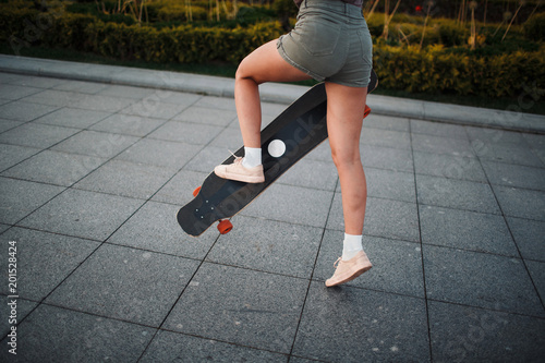 Young sporty woman riding on the longboard in the park