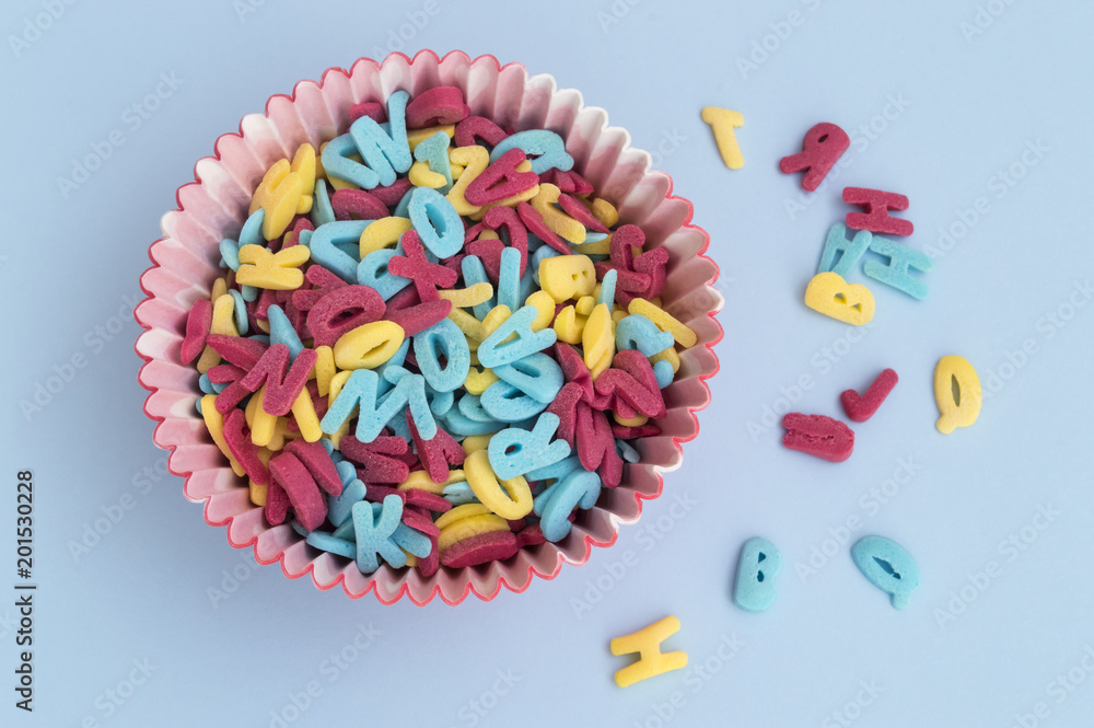 cupcake capsule filled with sugar letters on blue background