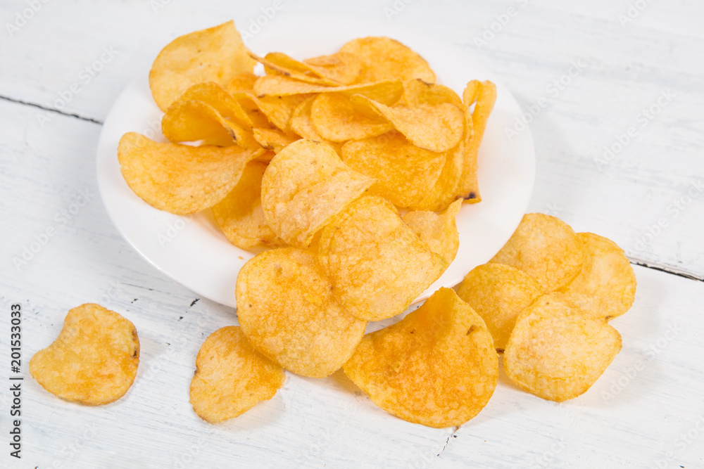 potato chips on white wooden background potato chips on white wooden background